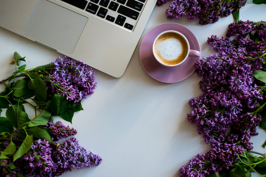 Floral composition made of beautiful purple lilac, syringa flowers on white background with cup of coffee. Feminine office desk, styled stock image, flat lay, top view with empty space.