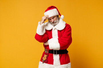 Fototapeta na wymiar Preoccupied elderly gray-haired mustache bearded Santa man in Christmas hat posing isolated on yellow background. Happy New Year 2020 celebration holiday concept. Mock up copy space. Put hand on head.