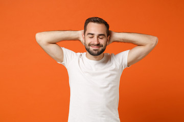 Relaxed young man in casual white t-shirt posing isolated on orange wall background, studio...
