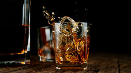 Splashing whiskey from glass with ice cubes inside