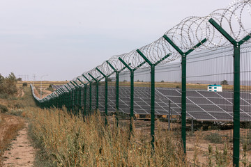 Solar power station protected from road by barbed wire fence. Fencing of sensitive sites with...
