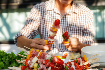 A man preparing barbecue outdoors for friends.