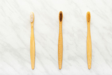 Bamboo toothbrushes on white marble background. Flat lay with copy space. Natural bath products. Biodegradable natural bamboo toothbrush. Eco friendly, Zero waste, Dental care Plastic free concept