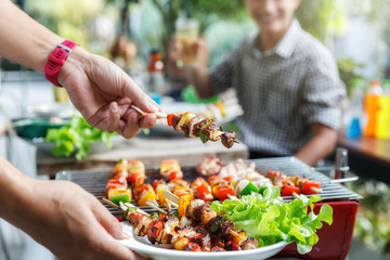 A man with a barbecue plate at a party between friends. Food, people and family time concept.