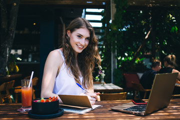 Talented woman smiling and taking notes