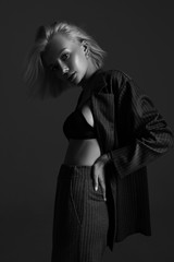 Portrait of elegant attractive girl in underwear and suit. Sexy fashion style woman model posing on black background in studio