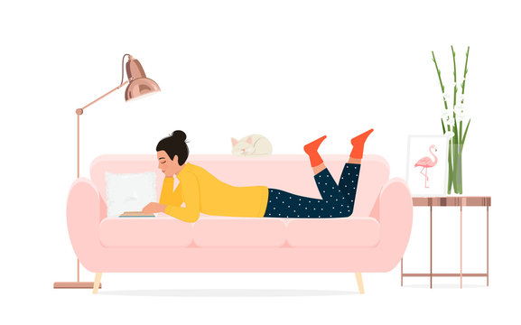 A girl reads a book on the couch.