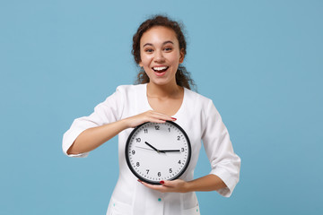 Cheerful african american female doctor woman in white medical gown holding round clock isolated on...