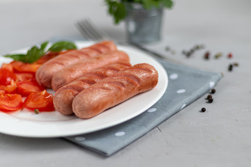 Breakfast of sausages and vegetables. Tomato sliced. On a light background.