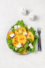 Fall harvest salad with  persimmon pomegranate rucola feta cheese. Top view, copy space.