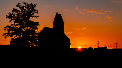 Obraz premium Beautiful sunset with a church and powerlines near Huett, Bavaria, Germany