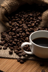 Espresso in a white cup and coffee beans close-up. Warm coffee tones.