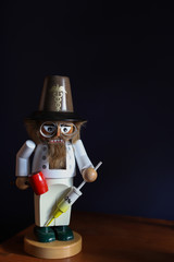 Vintage white, nutcracker chef on a dark background with a red hammer and syringe