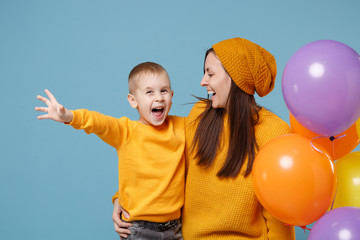 Fototapeta na wymiar Woman in yellow clothes have fun with cute child baby boy 4-5 years old celebrating birthday holiday party with colorful air balloons. Mommy son isolated on blue background. Family childhood concept.