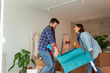 Couple carrying armchair while moving in new apartment