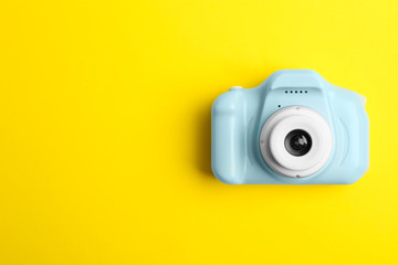Light blue toy camera on yellow background, top view with space for text. Future photographer