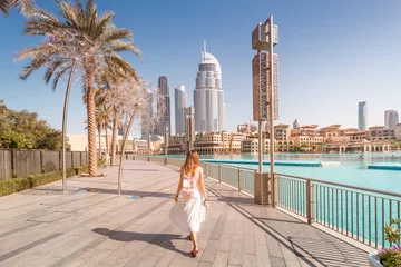 Tuinposter Dubai Gelukkig toeristenmeisje dat dichtbij fonteinen in de stad van Dubai loopt. Vakantie- en sightseeingconcept