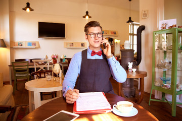 Small business owner young man working in his cafe