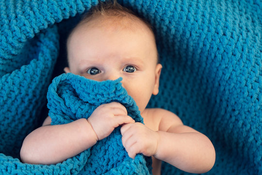 A Cute Baby Boy Hugging A Soft Blue Blanket