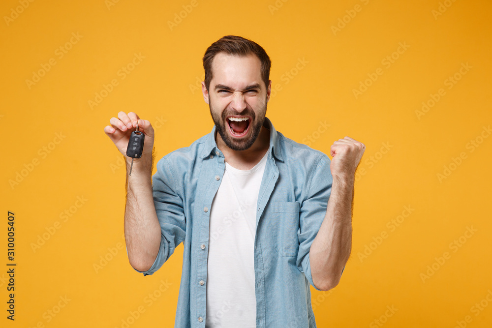 Wall mural happy young man in casual blue shirt posing isolated on yellow orange background, studio portrait. p