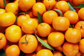 Fresh ripe tangerines with leaves as background, top view. Citrus fruit
