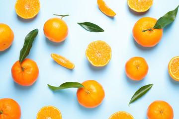 Flat lay composition with fresh ripe tangerines and leaves on light blue background. Citrus fruit