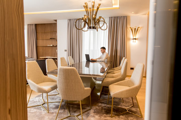 Young man sitting in a luxurious room in front of a laptop computer
