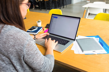 Female successful graphic designer creating new start up project on pc laptop computer while sitting at workstation in office interior.Woman lifestyle blogger typing article on web page via net-book