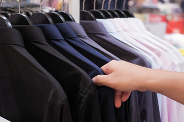 Cropped Hand Of Man choosing Men's shirts in clothing store