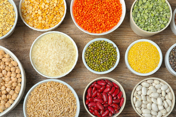 Different grains and cereals on wooden table, flat lay