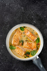Close up of salmon steaks in cream sauce on black background