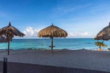 Beautiful view of white sand beach with sun umbrellas and sunbeds. Eagle beach. Aruba island.