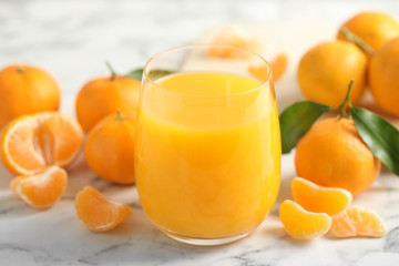 Glass of fresh tangerine juice and fruits on marble table