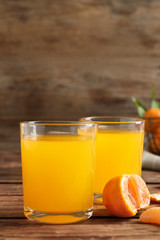 Glasses of fresh tangerine juice and fruits on wooden table
