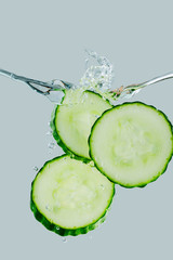 Three cucumber slices falling into the water splash