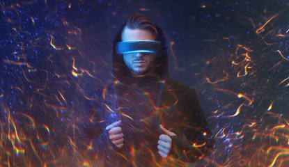 Young man on virtual reality background. Guy using VR helmet. Augmented reality, future technology, game concept. Blu neon light, fire flares.