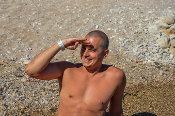 hombre torso desnudo en playa riendo