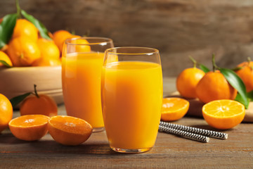 Glasses of fresh tangerine juice and fruits on wooden table
