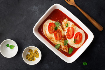 Baked chicken breast with cheese and tomato slices in a juicy tomato sauce on a baking sheet. Top view. Healthy eating,