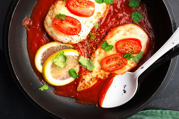 Baked chicken breast with cheese and tomato slices in a juicy tomato sauce on a baking sheet. Top view. Healthy eating,