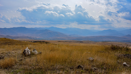 Obraz premium yellowed grass overlooking the mountains and clouds,rocky soil.