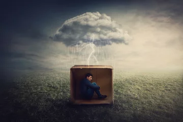 Fotobehang Surreal concept with a scared guy shelters inside a cardboard box. Introvert man caged by own fears as a thunderstorm cloud trapped him under the rain. Mysterious storm as emotional crisis symbol. © 1STunningART