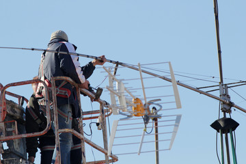 Worker on telescopic elevator repairing a antenna. Copy space