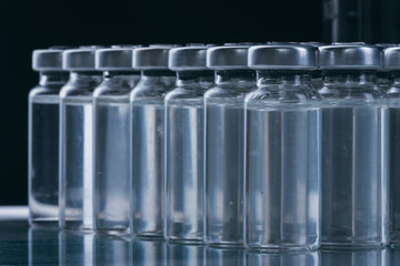 Glass medical ampoule vial for injection. Medicine is dry white drug penicillin powder or liquid with of aqueous solution in ampulla. Close up. Bottles ampule with aluminum cap on backgrounds gray.