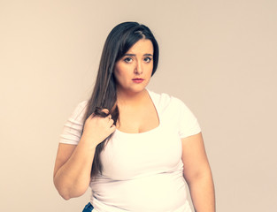Obraz premium Plus Size Model with long hair twists hair on a finger