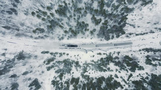 Aerial top down view steam train stay in snow covered spruce forest. Winter season