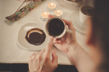 Coffee ground fortune teller, holding cup of coffee, close up