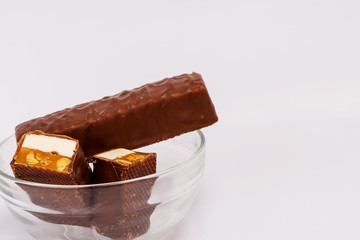 Chocolate bar on a white background. Chocolate-waffle bar with nut and caramel filling.