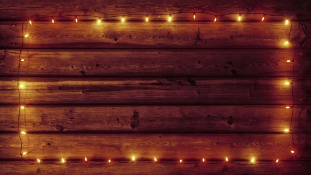 Christmas Lights Frame background loop, realistic garlands on old rustic wood plank, festive decorations, glowing and fading warm color lights. Merry Christmas and happy new year holiday 3d animation.