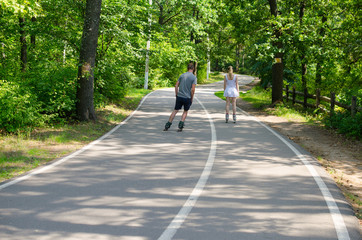 Guy and girl roller-skate on the track in the park